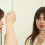 uma mulher de cabelo castanho e liso aplicando ácido hialurônico no rosto.