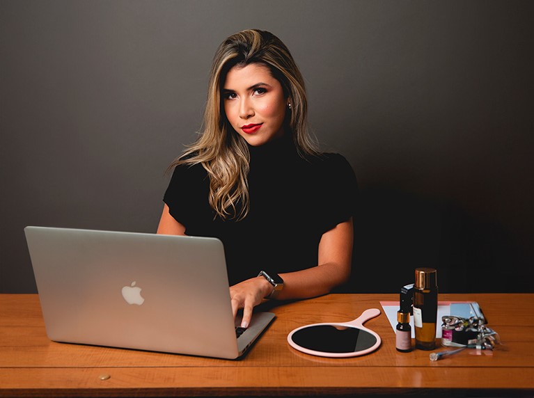 Esteticista Tayane Regis escrevendo em um macbook.